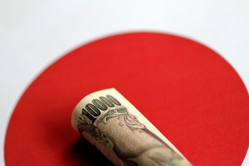 &copy; Reuters. Dettaglio di una banconota da 10.000 yen giapponesi sopra alla bandiera giapponese. REUTERS/Thomas White/