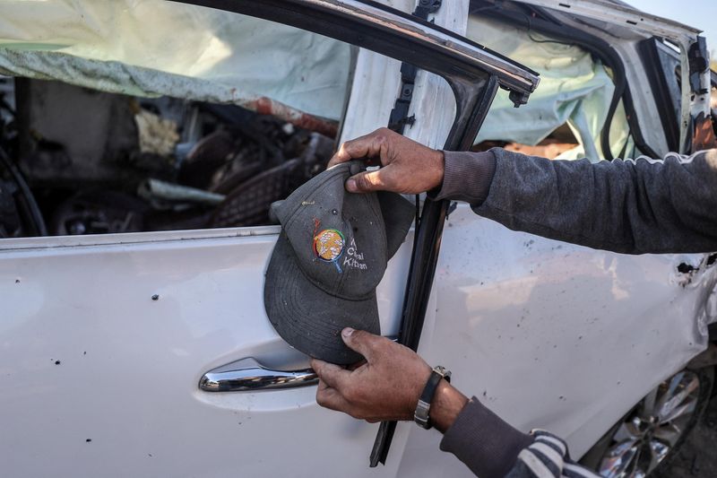 © Reuters. A person holds a cap next to a vehicle in which employees of the World Central Kitchen (WCK) were killed in an Israeli strike, according to WAFA, amid the ongoing conflict between Israel and Hamas, in Khan Younis in the southern Gaza Strip, November 30, 2024. REUTERS/Stringer