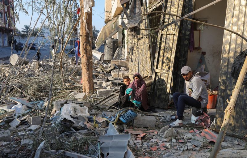 © Reuters. Palestinians sit amid rubble at the site of an Israeli strike on a house, amid the Israel-Hamas conflict, in Nuseirat in the central Gaza Strip December 1, 2024. REUTERS/Ramadan Abed