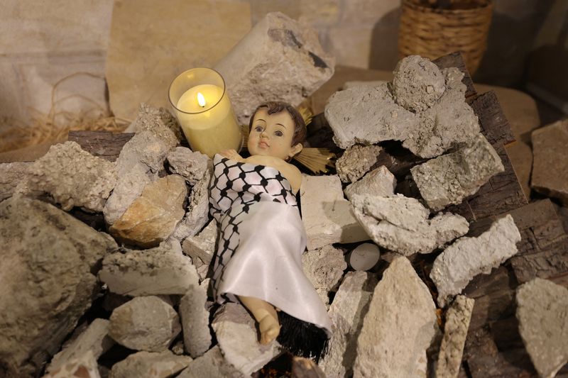 © Reuters. An installation of a figure symbolising baby Jesus lying amidst the rubble in a grotto ahead of Christmas at the Evangelical Lutheran Church in Bethlehem in the Israeli-occupied West Bank November 25, 2024. REUTERS/Mussa Qawasma