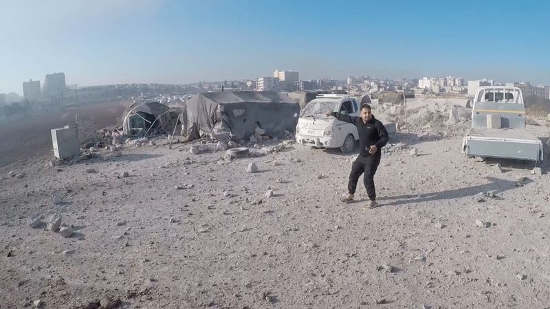 © Reuters. A man reacts near a damaged vehicle in the aftermath of what the White Helmets say is a strike, in Idlib, Syria, released December 1, 2024, in this still image taken from a handout video. The White Helmets/Handout via REUTERS 