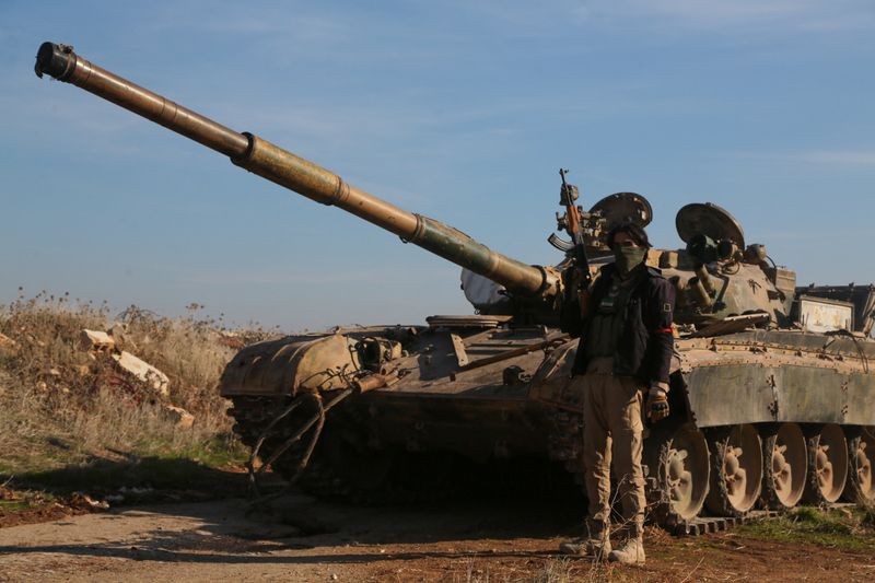 © Reuters. A rebel fighter holds his weapon as he stands in front of a military vehicle in Menagh, north of Aleppo, Syria December 2, 2024. REUTERS/Mahmoud Hassano