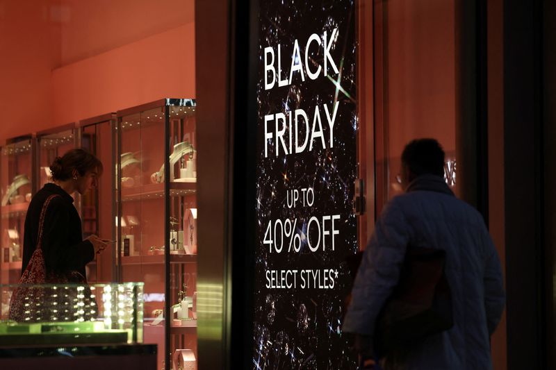 © Reuters. FILE PHOTO: A shopper enters a store with a Black Friday sale sign displayed on it, on Oxford Street in London, Britain November 28, 2024. REUTERS/Hollie Adams/File Photo