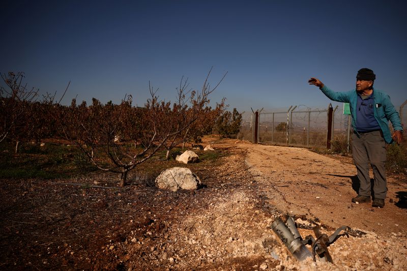 © Reuters. Moshe Weinstein, 76, an Israeli farmer stands near the remains of a rocket, launched from Lebanon, at his apple farm in Metula, Israel, December 1, 2024. REUTERS/Stoyan Nenov