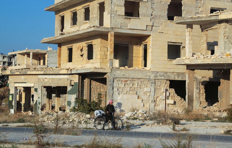 &copy; Reuters. FILE PHOTO: A man walks with his bike past damaged buildings in the town of Tel Rifaat, Syria December 2, 2024. REUTERS/Mahmoud Hassano/File Photo