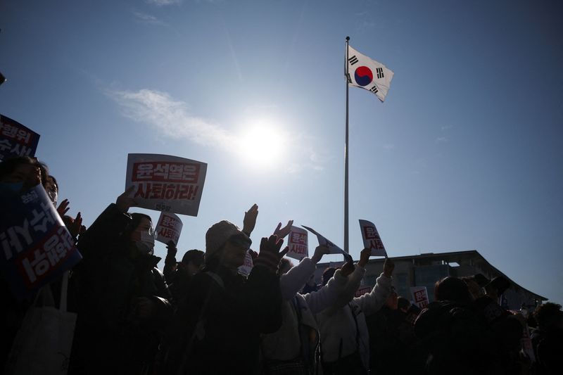 © Reuters. Protesters hold up signs as people and lawmakers attend a rally to condemn South Korean President’s surprise declarations of the martial law last night and to call for his resignation, at the national assembly in Seoul, South Korea, December 4, 2024. REUTERS/Kim Hong-Ji