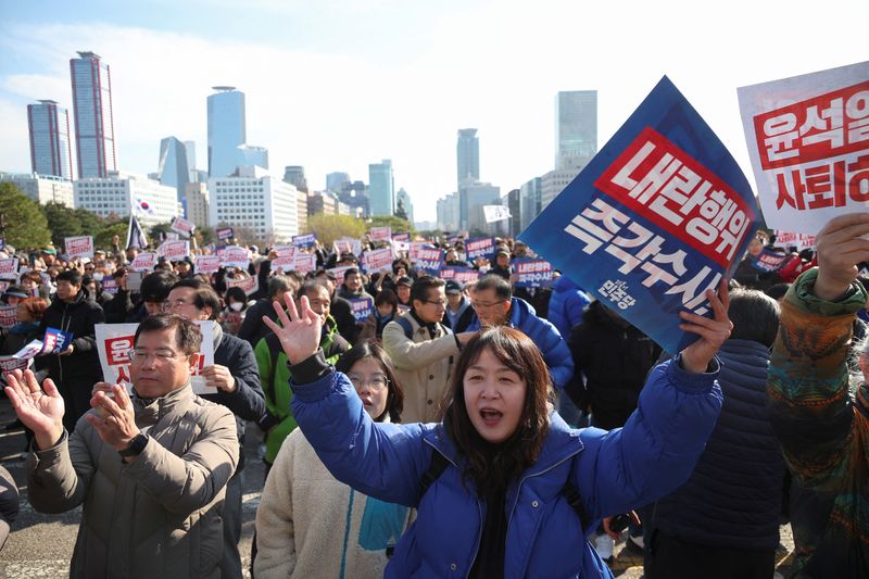 &copy; Reuters. People hold placards that read "Step down President Yoon Suk Yeol" and "Investigate his act of rebellion immediately", at a rally to condemn South Korean President’s surprise declarations of the martial law last night and to call for his resignation, at