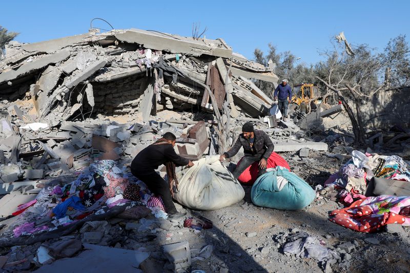 &copy; Reuters. Palestinesi raccolgono oggetti sul luogo di un attacco israeliano a una casa, durante il conflitto tra Israele e Hamas, a Deir Al-Balah, nella Striscia di Gaza centrale, il 4 dicembre 2024. REUTERS/Ramadan Abed