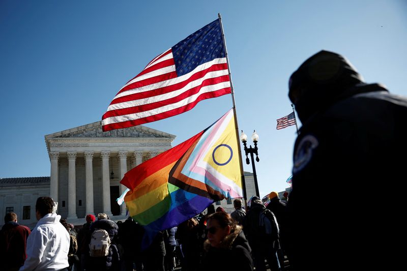 © Reuters. People hold flags at a demonstration, as the U.S. Supreme Court hears arguments over an appeal by U.S. President Joe Biden's administration of a lower court's decision upholding a Republican-backed ban in Tennessee on gender-affirming medical care for transgender minors, outside the court in Washington, U.S., December 4, 2024. REUTERS/Benoit Tessier