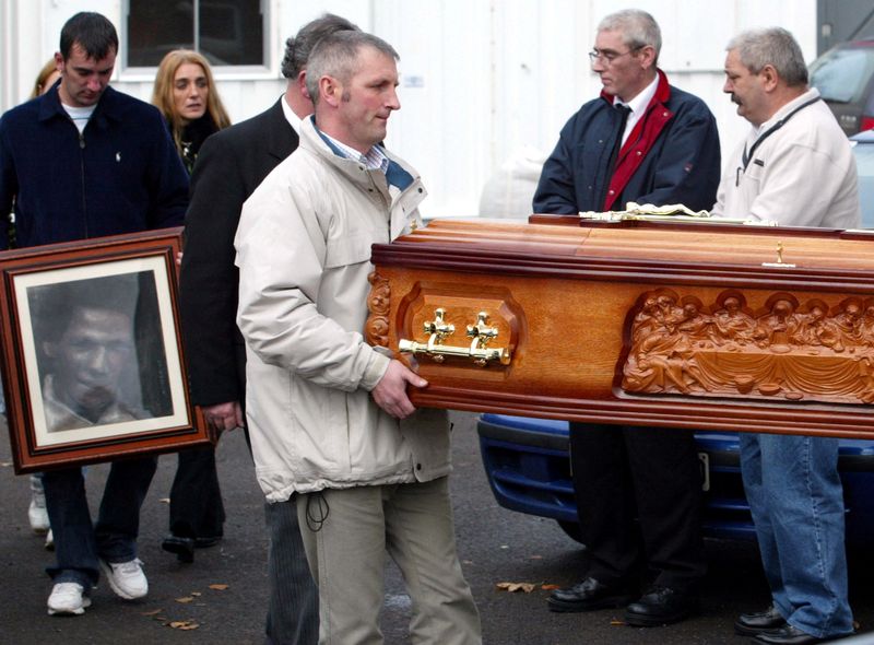 &copy; Reuters. FILE PHOTO: A family member carries a picture of murdered Belfast mother Jean McConville, while other unidentified family members carry her coffin into a family house in the small County Antrim village of Crumlin, Northern Ireland, October 30, 2003. . REU