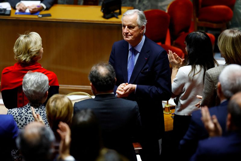 © Reuters. French Prime Minister Michel Barnier is applauded by members of the French government after he delivered a speech during a debate on two motions of no-confidence against the French government, tabled by the alliance of left-wing parties the 