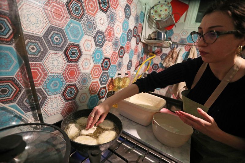 &copy; Reuters. Artist Gogona Parkaia, 25, cooks mchadi, a traditional Georgian cornbread, to distribute to supporters of Georgia's opposition parties protesting against the government's decision to suspend talks on joining the European Union, in Tbilisi, Georgia Decembe