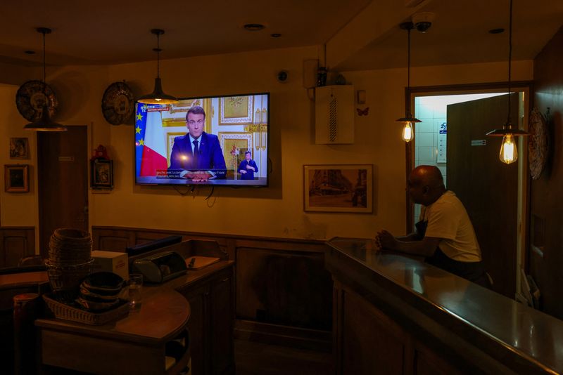 © Reuters. A man looks at a screen in a cafe showing French President Emmanuel Macron delivering a televised address to the nation after Prime Minister Michel Barnier's government was ousted in a no-confidence vote in Paris, France, December 5, 2024. REUTERS/Kevin Coombs