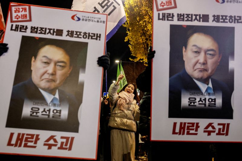 © Reuters. Protesters hold placards during a candlelight vigil to condemn South Korean President Yoon Suk Yeol's surprise declarations of the failed martial law and to call for his resignation in Seoul, South Korea, December 5, 2024. REUTERS/Kim Kyung-Hoon