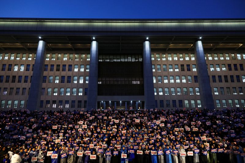 © Reuters. People hold candles and signs during a candlelight vigil to demand the resignation of South Korean President Yoon Suk Yeol, who declared martial law which was reversed hours later, at the National Assembly in Seoul, South Korea, December 5, 2024. REUTERS/Kim Hong-ji