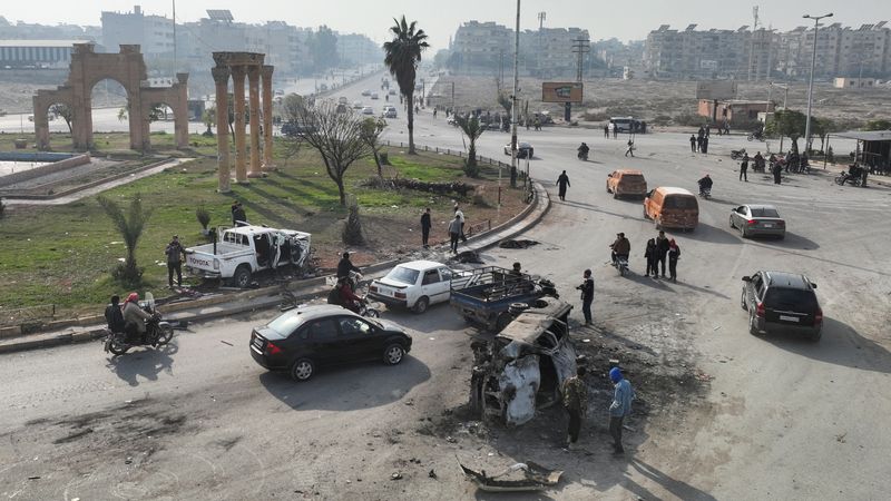 © Reuters. People stand near a damaged vehicle, after HTS-led rebels sought to capitalize on their rapid takeover of Aleppo in the north and Hama in west-central Syria by heading towards Homs , in Hama, Syria, December 6, 2024. REUTERS/Mahmoud Hasano