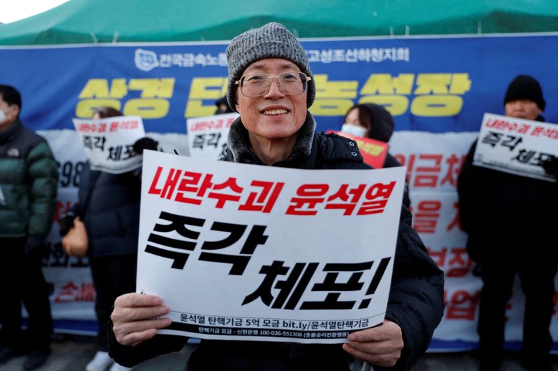 © Reuters. Lee Chul-woo, 70, who was tortured during the student democracy movement in the 80's and took part in rallies against the regime of former South Korean President Lee Myung-bak and Park Geun-hye, holds a banner that reads 'Arrest Yoon Suk Yeol right now' during a rally to demand the resignation of South Korean President Yoon Suk Yeol, in Seoul, South Korea, December 6, 2024. REUTERS/Kim Soo-hyeon