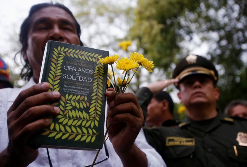 &copy; Reuters. Um residente com flores e um livro "Cem Anos de Solidão" do prêmio Nobel colombiano García Márquez, participa de funeral público simbólico de García Márquez, em Aracatacan21/04/2014nREUTERS/John Vizcaino