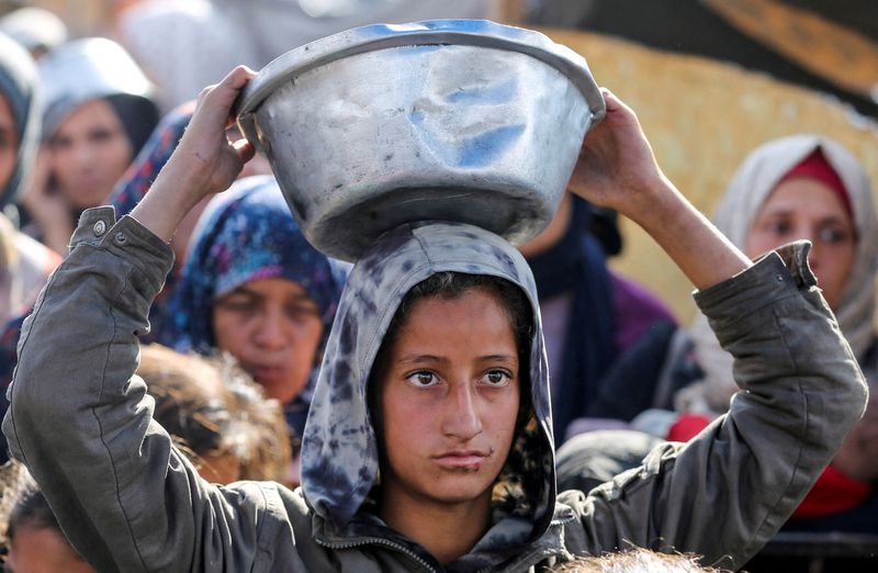 © Reuters. Palestinians gather to receive food cooked at a charity kitchen, before a ceasefire between Hamas and Israel takes effect, in Khan Younis, in the southern Gaza Strip, January 17, 2025. REUTERS/Hatem Khaled   