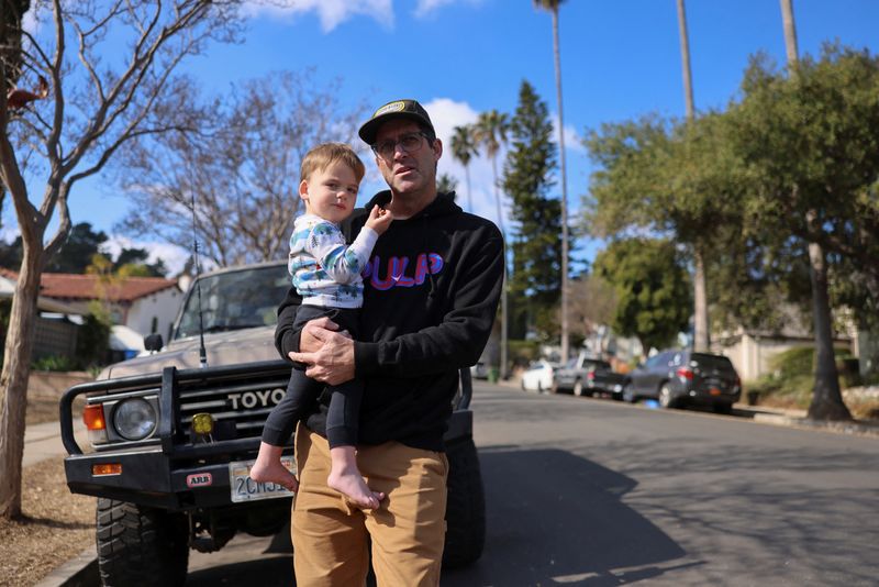 &copy; Reuters. John Adolf holds his son Remey, as he stays with his friends after his home in Altadena was damaged during the Eaton Fire, in Eagle Rock, California, U.S., January 17, 2025. REUTERS/David Swanson