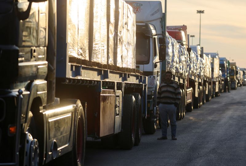 © Reuters. A man stands next to trucks carrying aid waiting at the Rafah border crossing between Egypt and the Gaza Strip, amid a ceasefire between Israel and Hamas, in Rafah, Egypt, the January 19, 2025. REUTERS/Mohamed Abd El Ghany