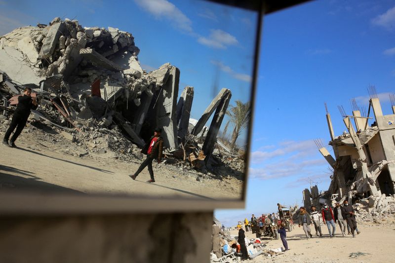 &copy; Reuters. Palestinians walk past the rubble of houses and buildings destroyed during the war, following a ceasefire between Israel and Hamas, in Rafah in the southern Gaza Strip, January 20, 2025. REUTERS/Hatem Khaled 