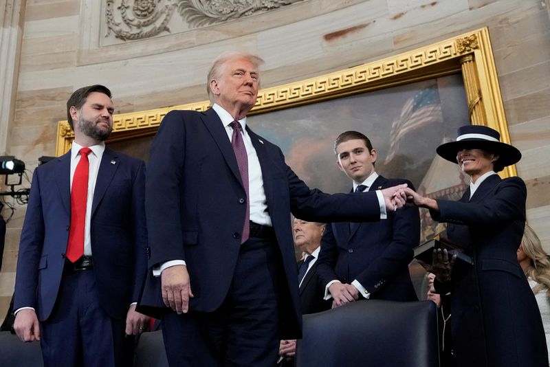 © Reuters. U.S. President Donald J. Trump, center, holds the hand of his wife Melania Trump, right, as their son Barron Trump, center, and Vice President JD Vance, look on after taking the oath of office during the 60th Presidential Inauguration in the Rotunda of the U.S. Capitol in Washington, Monday, Jan. 20, 2025.     Morry Gash/Pool via REUTERS