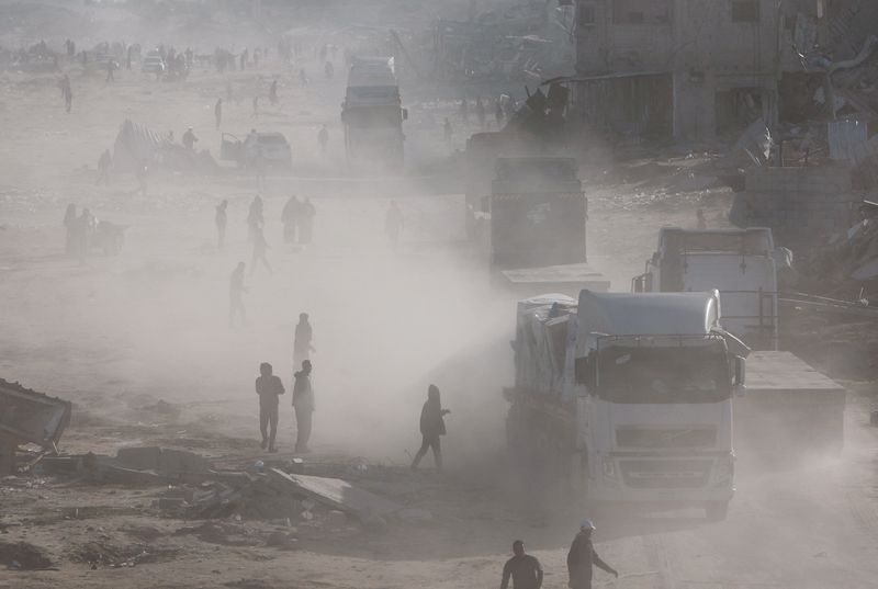 © Reuters. Palestinians rush to take aid from moving trucks entering Rafah, following a ceasefire between Israel and Hamas, in the southern Gaza Strip, January 20, 2025. REUTERS/Mohammed Salem   
