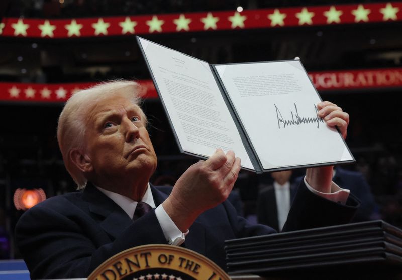 © Reuters. U.S. President Donald Trump presents an executive order during the inaugural parade inside Capital One Arena on the inauguration day of his second presidential term, in Washington, U.S. January 20, 2025. REUTERS/Carlos Barria