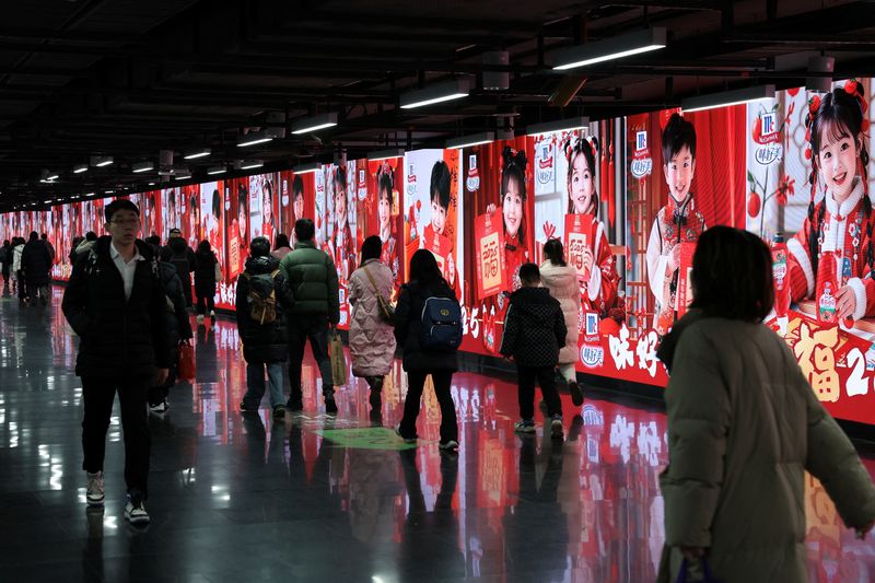 © Reuters. FILE PHOTO: People walk in front of billlboards in a metro station in Shanghai, China, January 16, 2025. REUTERS/Go Nakamura/File Photo