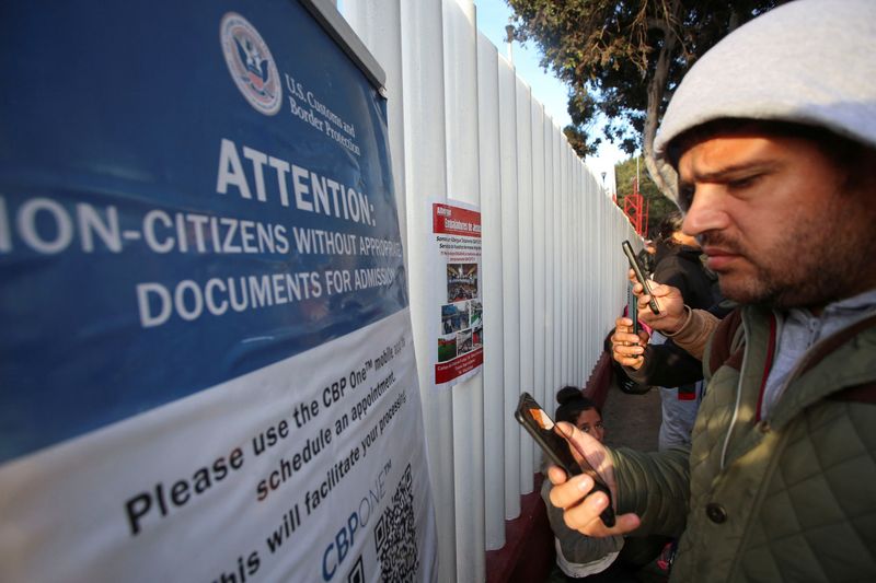 &copy; Reuters. FILE PHOTO: Migrants check their phones while gathering at El Chaparral border crossing after their CBP One app asylum appointment was cancelled on the day of U.S. President Donald Trump's inauguration, in Tijuana, Mexico January 20, 2025. REUTERS/Jorge D