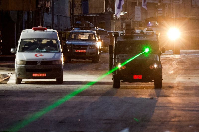 © Reuters. An Israeli military vehicle uses a laser, on the day of an Israeli raid in Jenin, in the Israeli-occupied West Bank, January 21, 2025. REUTERS/Raneen Sawafta     