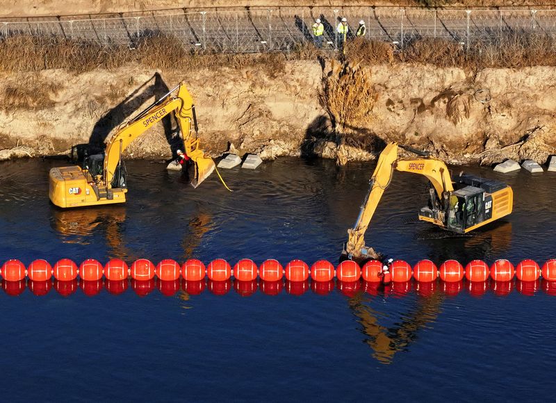 © Reuters. A drone view shows U.S. workers assembling a string of buoys, to deter migrants from crossing the Rio Grande river from Mexico into Eagle Pass, Texas, as seen from Piedras Negras, Mexico January 21, 2025. REUTERS/Alberto Fajardo