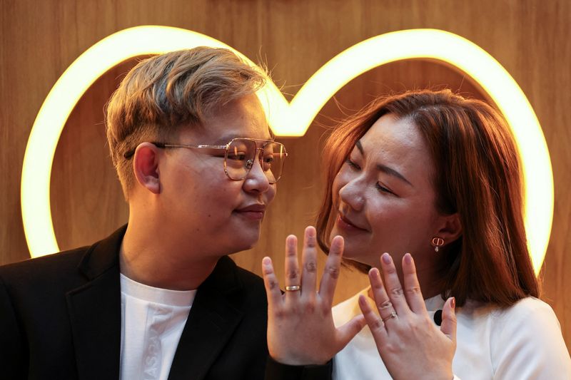 © Reuters. An LBGTQ+ couple, Pawan Iamwet, 35, and Kamonchanok Chumruan, 38, pose for a picture as they wait to receive official marriage certificates, as the country's marriage equality bill comes into effect following a royal endorsement which effectively makes Thailand Asia's third territory to legalise same-sex unions, in Bangkok, Thailand, January 23, 2025. REUTERS/Chalinee Thirasupa