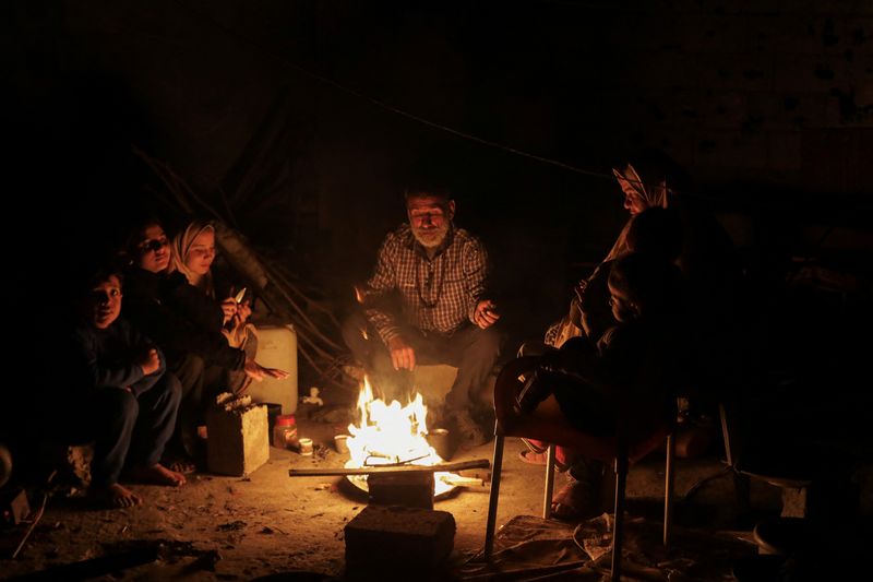 &copy; Reuters. FILE PHOTO: Palestinians sit next to a fire, amid a ceasefire between Israel and Hamas, in Jabalia in the northern Gaza Strip, January 22, 2025. REUTERS/Mahmoud Issa/File Photo