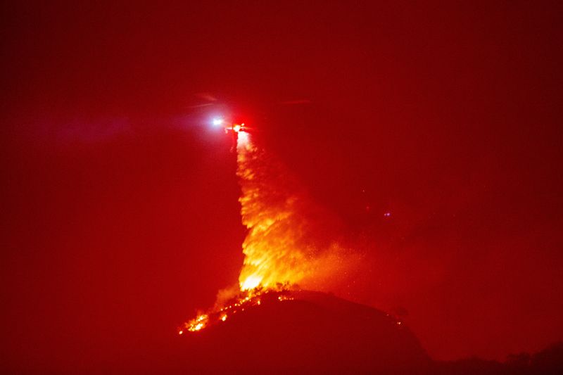 &copy; Reuters. A helicopter drops water as the Hughes Fire burns near Castaic Lake, north of Santa Clarita, California, U.S. January 22, 2025.  REUTERS/Ringo Chiu