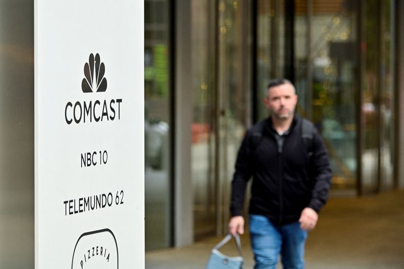 &copy; Reuters. FILE PHOTO: A person walks near a sign at the entrance of the Comcast Technology Center located at on of the two towers forming the corporate headquarters of Comcast, which announced plans to spin-off the bulk of its fading NBCUniversal cable TV networks,