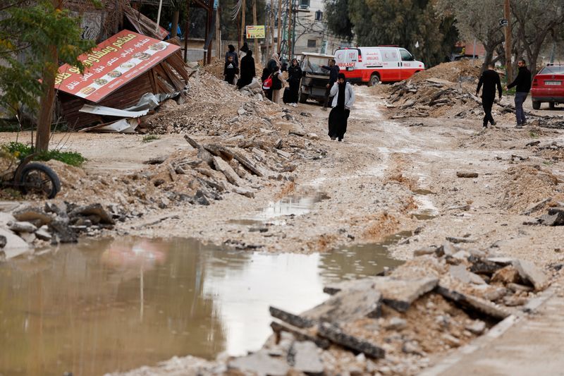 © Reuters. Palestinians walk on a damaged street in Jenin camp during an Israeli raid, in the Israeli-occupied West Bank, January 23, 2025. REUTERS/Raneen Sawafta