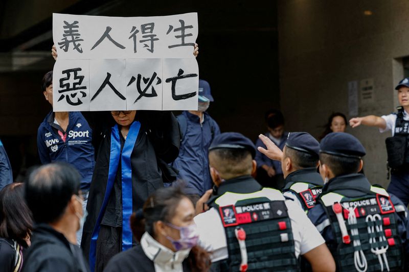 © Reuters. FILE PHOTO: Elsa, the foster mother of one of the defendants, social worker Hendrick Lui, holds a banner reading 