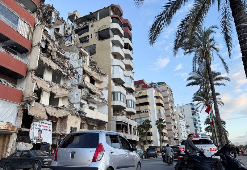 © Reuters. Cars drive past a damaged building near the Corniche, after the Israeli prime minister's office said on Friday that Israeli forces will remain in southern Lebanon beyond a 60-day deadline stipulated in a ceasefire deal with Hezbollah because its terms have not been fully implemented, in Tyre, Lebanon January 24, 2025. REUTERS/Ali Hankir