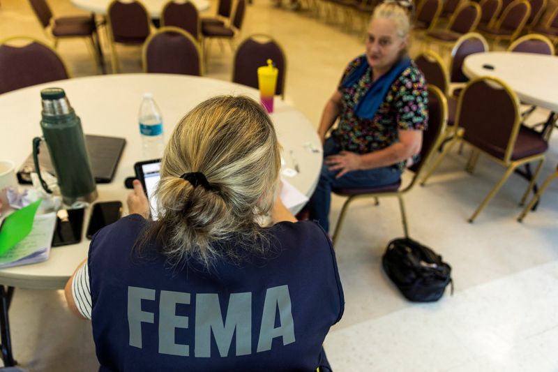 © Reuters. FILE PHOTO: A Federal Emergency Management Agency worker attends to a claim from a local resident after being affected by flooding following the passage of Hurricane Helen, in Marion, North Carolina, US, October 5, 2024. REUTERS/Eduardo Munoz/File Photo