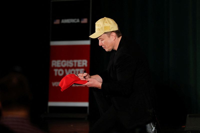 © Reuters. FILE PHOTO: Tesla CEO and X owner Elon Musk, who supports Donald Trump, signs a cap during an America PAC Town Hall in Folsom, Pennsylvania, U.S., October 17, 2024. REUTERS/Rachel Wisniewski/File photo