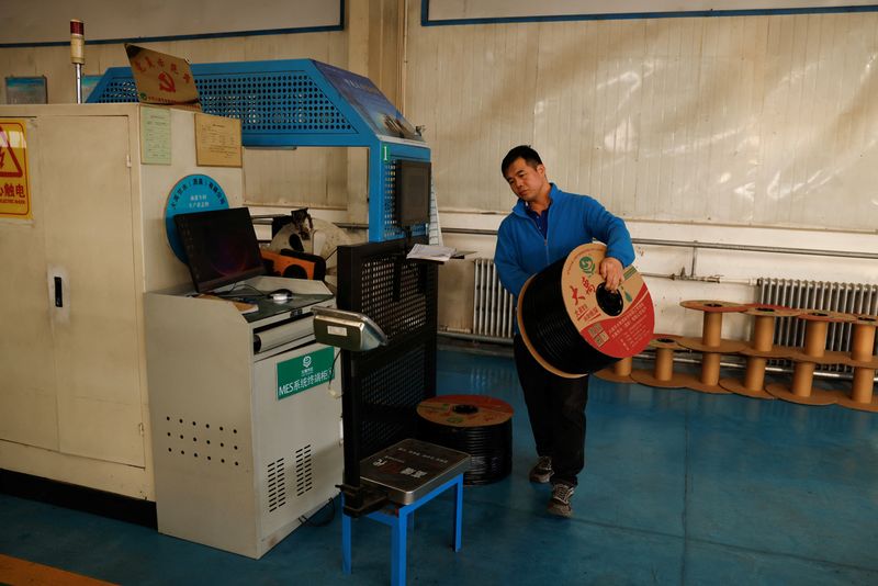 © Reuters. FILE PHOTO: A worker carries a roll of drip tape at a factory of DAYU Water Group Co, in Jiuquan, during an organised media tour in Gansu province, China October 18, 2024. REUTERS/Tingshu Wang/File Photo