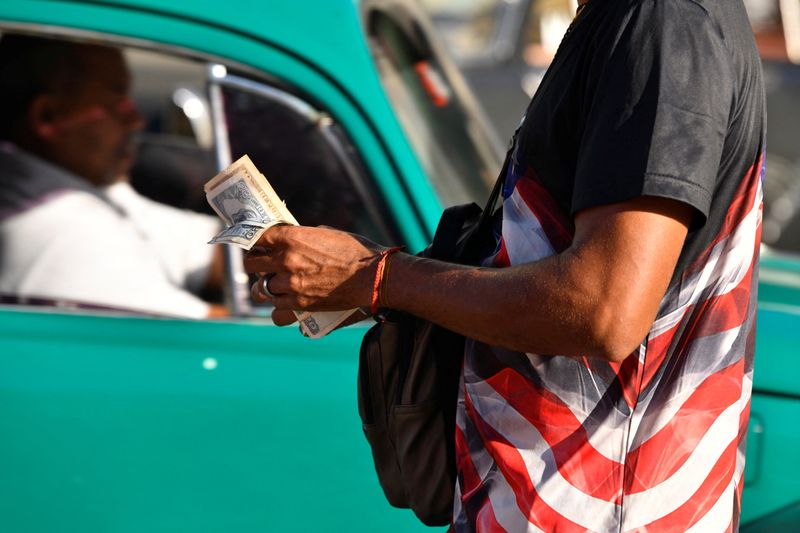 &copy; Reuters. Homem com uma nas cores dos EUA com maço de pesos cubanos em Havanan10/02/2025nREUTERS/Norlys Perez