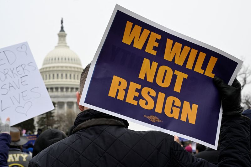 &copy; Reuters. Pessoa exibe placa enquanto ativistas sindicais se manifestam em apoio aos trabalhadores federais com o Capitólio ao fundo em Washington, EUAn11/02/2025nREUTERS/Craig Hudson