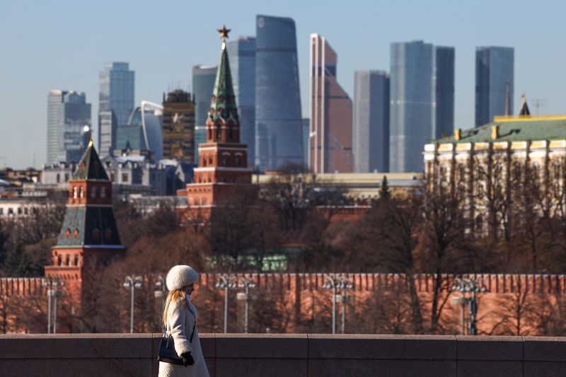 &copy; Reuters. Una donna cammina su un ponte davanti al polo finanziario del centro di Mosca, osservabile sullo sfondo dietro le mura del Cremlino, Russia, 24 febbraio 2025. REUTERS/Evgenia Novozhenina