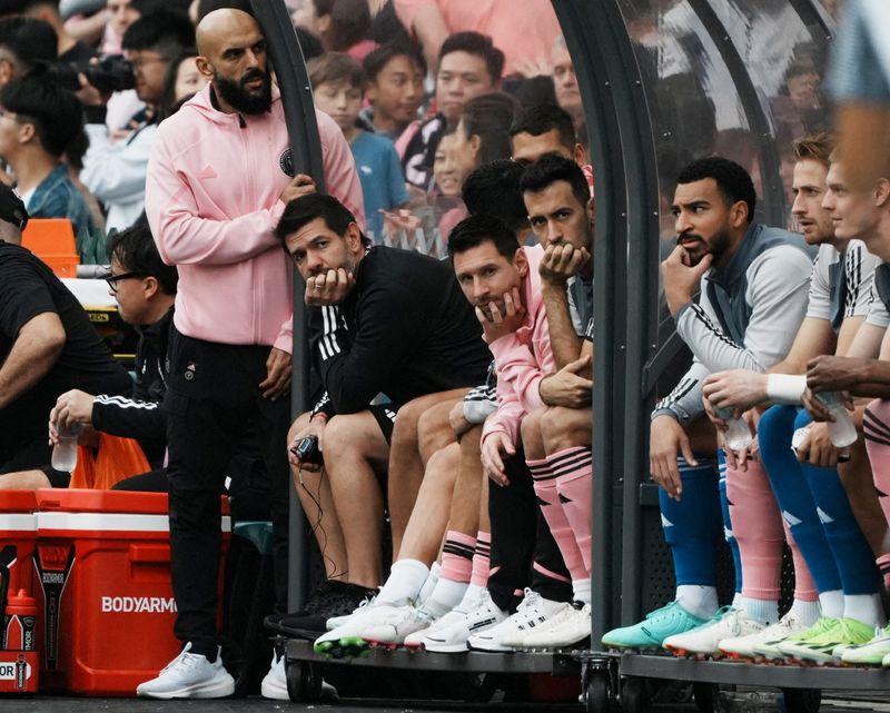&copy; Reuters. Lionel Messi e companheiros de equipe do Inter Miami sentam-se no banco de reservas durante jogo amistoso enquanto o segurança de Messi, Yassine Cheuko, observan04/02/2024nREUTERS/Lam Yik