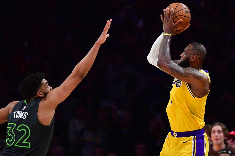 © Reuters. LeBron James au duel avec Karl-Anthony Towns. /Photo prise le 12 avril 2023/REUTERS/USA Today Sports